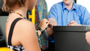 Ein Kind gibt dem Busfahrer ein Ticket.