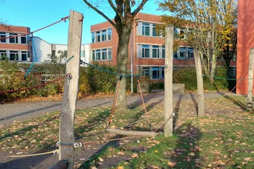 Blick auf den Niedrigseilgarten an der Seite des Neubaus, im Hintergrund die Rückseite des Hauptgebäudes. Der Niedrigseilgarten wird besonders vom Jahrgang 5 in den Pausen genutzt.