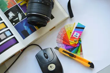 Ein Buch, eine Kamera, eine PC-Maus, ein Cuttermesser und eine Farbskala