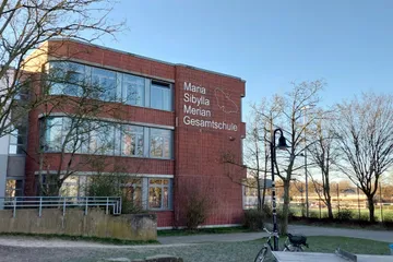 Schullogo aus Aluminium am A-Trakt außen, mit Blick in Richtung Sportplatz