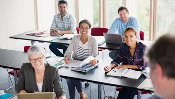 Kinder springen auf einer Wiese mit hoch erhobenen Armen. Der Himmel ist blau, und es gibt grüne Bäume. Sie tragen bunte Kleidung und lachen im Sonnenschein.