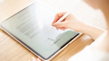 Jemand unterschreibt ein Dokument auf einem Tablet.