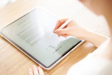 Jemand unterschreibt ein Dokument auf einem Tablet.